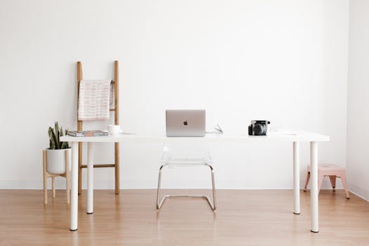 Home Bright and minimalist home office setup with a white desk, laptop, and potted plant.